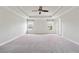 Spacious primary bedroom features trey ceiling, a ceiling fan, neutral carpeting, and windows offering views at 6043 China Rose Lane, Johns Creek, GA 30097