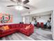 Bright living room features a ceiling fan, red couch, gray flooring and an open dining area at 6487 Northridge Way, Morrow, GA 30260