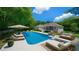 A luxurious in-ground pool with lounge seating, sofa, and umbrella creates an inviting outdoor space at 1460 Bakers Bridge Rd, Douglasville, GA 30134