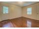 Empty bedroom featuring warm-toned hardwood floors, neutral walls, and natural light from two windows at 2690 Ross Rd, Snellville, GA 30039