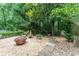 Charming backyard retreat with stone accents, garden decor, mature trees and a cozy fire pit area for outdoor enjoyment at 3745 Meeting St, Duluth, GA 30096