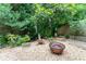 Relaxing backyard with a copper fire pit, gravel, garden decor and stepping stone pathway through lush greenery at 3745 Meeting St, Duluth, GA 30096