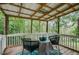 Charming covered porch with seating and a table, ideal for enjoying the serene wooded surroundings at 41 Wexford Nw Cir, Cartersville, GA 30121