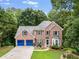 Charming two-story brick home with blue garage doors, lush lawn, and mature trees at 41 Wexford Nw Cir, Cartersville, GA 30121