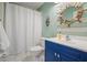 Charming bathroom features a blue vanity, white tile floors, and nautical decor with a ship wheel mirror at 1680 Laleiah Dr, Cumming, GA 30041