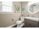 Neutral toned powder room with dark wood vanity and framed mirror at 1680 Laleiah Dr, Cumming, GA 30041