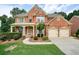 Beautiful two-story brick home featuring a covered front porch and a two-car garage at 1680 Laleiah Dr, Cumming, GA 30041