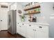 Bright kitchen with stainless refrigerator, white cabinets, and decorative shelves at 1680 Laleiah Dr, Cumming, GA 30041