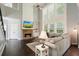 Spacious living room with stone fireplace, large windows, and dark hardwood floors at 1680 Laleiah Dr, Cumming, GA 30041