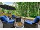 Close-up of patio seating area with plush blue cushions, a fire pit, and a view of the surrounding trees at 1680 Laleiah Dr, Cumming, GA 30041