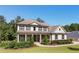 Charming two-story home featuring a welcoming front porch and a beautifully landscaped front yard under a clear blue sky at 140 Discovery Lake Dr, Fayetteville, GA 30215