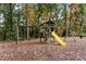Backyard with a wooden playset featuring a slide and swings surrounded by mature trees and leafy ground at 3083 Colonial Way # E, Atlanta, GA 30341