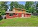 Home with a red brick and light wood exterior with a small concrete patio in the green backyard at 1177 Castle Way Way, Norcross, GA 30093