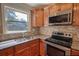 Close-up of kitchen area featuring stainless steel appliances, granite countertops, tile backsplash, and wood cabinetry at 1177 Castle Way Way, Norcross, GA 30093