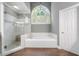Bathroom showcasing a soaking tub with white tile surround, separate shower, and a large window for natural light at 1360 Wilmington Way, Grayson, GA 30017