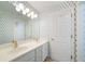 Bright bathroom featuring a dual vanity, stylish mirror and unique floral leaf patterned wallpaper at 1360 Wilmington Way, Grayson, GA 30017