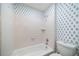 Bathroom featuring a tub and shower with tiled walls and a toilet with a blue patterned wallpaper accent wall at 1360 Wilmington Way, Grayson, GA 30017