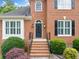 Close-up of the brick home's front door with arched window, black shutters and decorative landscaping at 1360 Wilmington Way, Grayson, GA 30017