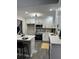 Modern kitchen featuring white cabinets, bar seating, stainless steel appliances, and gray flooring at 539 Rue Montaigne, Stone Mountain, GA 30083