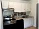 Compact kitchen featuring white cabinets, black appliances, and tiled backsplash at 210 Ormond Sw St, Atlanta, GA 30315