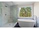 Modern bathroom featuring a glass shower, soaking tub, and a serene view from the large window at 410 Hickory Fairway Ct, Woodstock, GA 30188