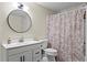Bathroom features a round mirror, single sink vanity and a shower/tub combo with a palm patterned shower curtain at 410 Hickory Fairway Ct, Woodstock, GA 30188