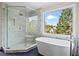 Modern bathroom with a glass shower, soaking tub, and large window offering bright, natural light at 410 Hickory Fairway Ct, Woodstock, GA 30188