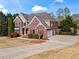 Charming two-story brick home featuring a well-manicured lawn, mature trees, and a long driveway at 410 Hickory Fairway Ct, Woodstock, GA 30188
