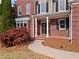 Charming brick home featuring a covered front entrance with decorative door and manicured landscaping at 410 Hickory Fairway Ct, Woodstock, GA 30188