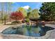 Inviting pool area with lush landscaping, a small rock waterfall, and a wooden fence at 410 Hickory Fairway Ct, Woodstock, GA 30188
