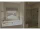 Bathroom featuring a tub and shower with tile and a window for natural light at 505 Mirror Lake Pkwy, Villa Rica, GA 30180