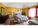 This bedroom features gold walls, a comfy bed, bedside tables, and red curtains that add a pop of color to the decor at 7101 Brecken Pl, Lithonia, GA 30058