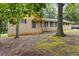 A single-story brick home features black shutters, complemented by the shade of mature trees in the front yard at 574 Horseshoe Sw Cir, Lilburn, GA 30047