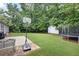 Spacious backyard featuring lush green grass, a basketball hoop, and a trampoline, perfect for outdoor activities at 784 Crestworth Xing, Powder Springs, GA 30127