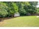 Spacious backyard featuring a storage shed, a trampoline, and bordered by mature trees at 784 Crestworth Xing, Powder Springs, GA 30127