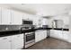 Bright kitchen features white cabinets, stainless appliances, black countertops, and tile floors at 784 Crestworth Xing, Powder Springs, GA 30127
