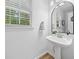 Stylish powder room with a pedestal sink, decorative mirror, and natural light at 150 Kensley Way, Dallas, GA 30157