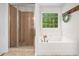 Bright bathroom featuring a tiled shower and a relaxing soaking tub under a window at 150 Kensley Way, Dallas, GA 30157