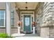 Inviting front porch with stone accents and a teal front door with sidelights at 4154 Hawking Dr, Suwanee, GA 30024