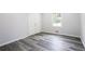 Bright bedroom featuring modern gray wood flooring, white walls, a double-door closet, and a window offering ample natural light at 6000 Malibu Drive Dr, Morrow, GA 30260