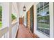 Spacious covered porch with classic brick flooring, white railings, and pendant lights at 6000 Malibu Drive Dr, Morrow, GA 30260