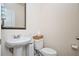 Clean half bathroom featuring a pedestal sink, toilet, neutral walls, and decorative mirror for guests at 149 Woodhouse Cir, Acworth, GA 30102