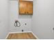 Compact laundry room features wood-look flooring, wall-mounted cabinet and utility connections at 56 Carlane Cir, Bowdon, GA 30108