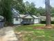 Charming single-story home with a covered front porch, lush green lawn, and mature trees providing shade at 2225 Baker Nw Ter, Atlanta, GA 30318