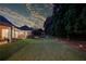 Inviting backyard at dusk featuring manicured lawn, mature trees, and subtle landscape lighting at 3468 Aberrone Pl, Buford, GA 30519