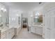 Bright, open bathroom with double sinks, a tub, decorative walls and neutral-toned tile flooring at 3468 Aberrone Pl, Buford, GA 30519