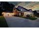 Home exterior at twilight with lit, attached two-car garage and columned porch at 3468 Aberrone Pl, Buford, GA 30519
