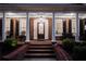 Inviting front porch at twilight, featuring a decorative front door, rocking chairs, and detailed trim at 3468 Aberrone Pl, Buford, GA 30519