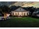 Charming single-story brick home at dusk, featuring a columned porch and well-manicured lawn at 3468 Aberrone Pl, Buford, GA 30519