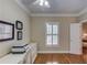Neutral home office with pristine hardwood floors and natural light, featuring a printer and shuttered window at 3468 Aberrone Pl, Buford, GA 30519